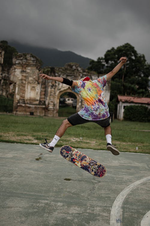 Man in Colorful Shirt Jumping on Skateboard