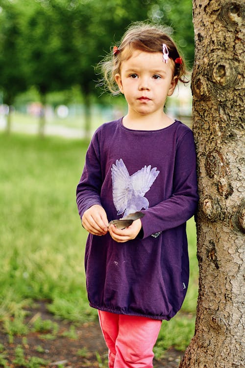 A Girl in Purple Long Sleeve Dress Standing Beside Tree