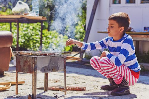 Free A Boy Sitting Beside the Barbecue Grill
 Stock Photo