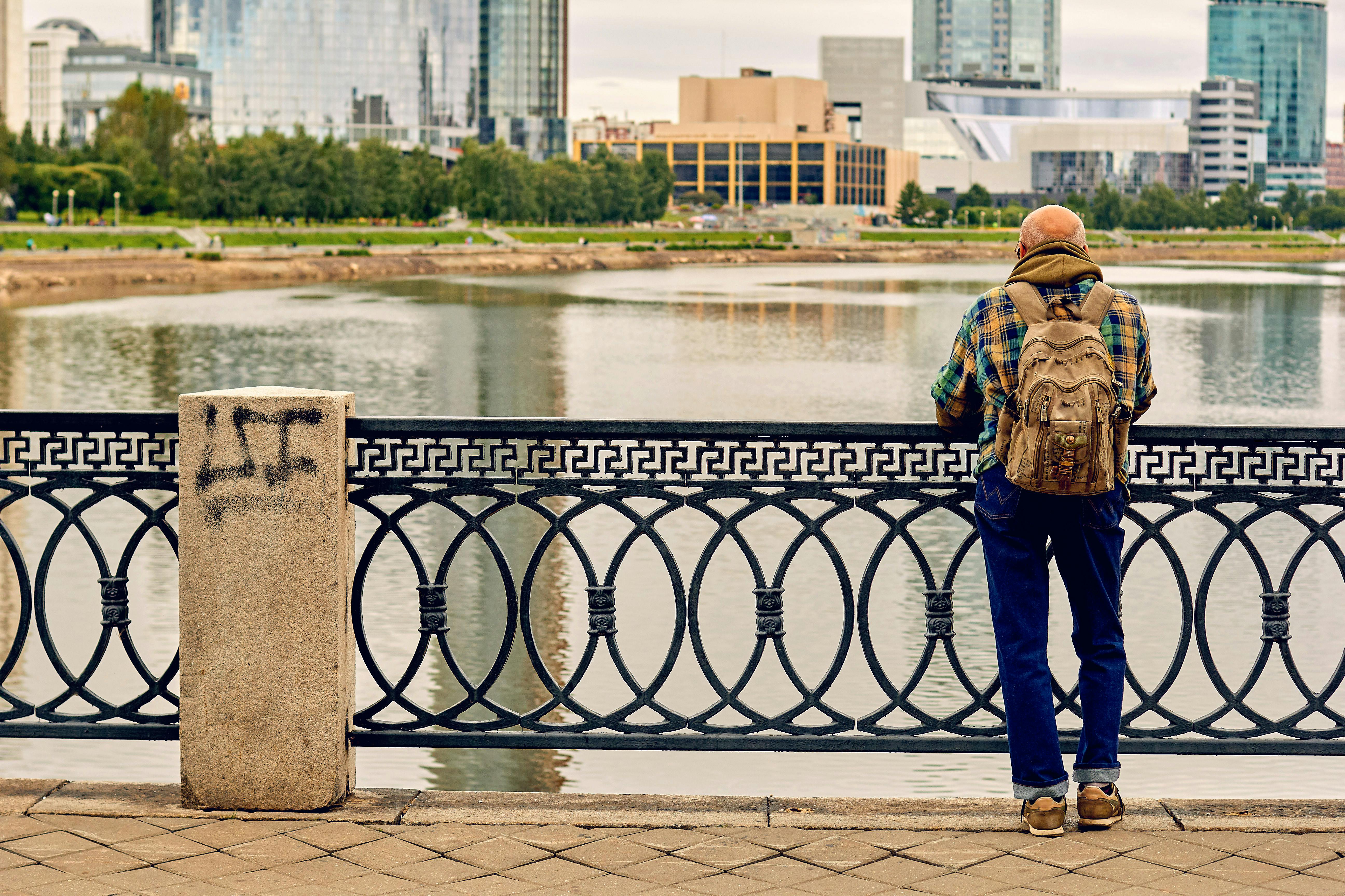 Man Standing Near Black Metal Fence Bridge