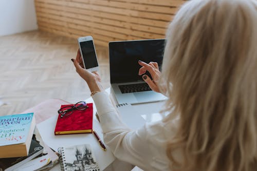 Woman in White Long Sleeve Shirt Holding Black Smartphone