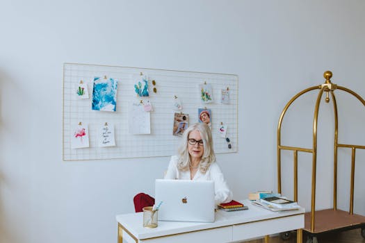 白发老妇人在时尚办公桌前使用笔记本电脑，展现了现代化的工作环境