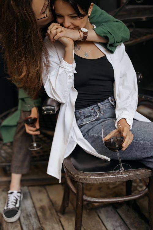 Free A cozy, affectionate moment between a couple enjoying glasses of wine outdoors. Stock Photo