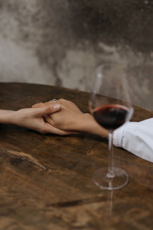 Free Close-up of hands holding with red wine glass, setting a romantic tone. Stock Photo