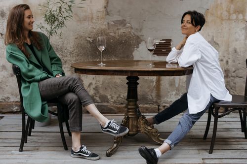Free Two women enjoying a relaxed conversation over wine at an outdoor table. Stock Photo