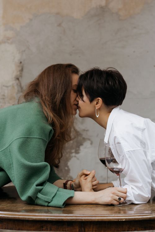 Free A loving moment between a lesbian couple enjoying a glass of wine indoors. Stock Photo