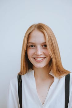 这幅明亮开朗的肖像描绘了一位留着金色长发、面带柔和微笑的女子，背景以浅色调映衬