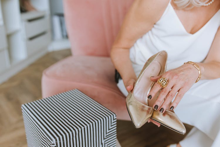 A Person's Hands Holding Shoes