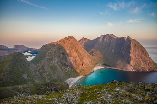 From above of picturesque seascape with rocky mountains in Vesteralen Islands against sunset sky