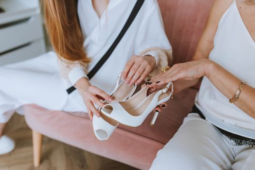Free Two women presenting elegant white high heels in a stylish indoor setting. Stock Photo