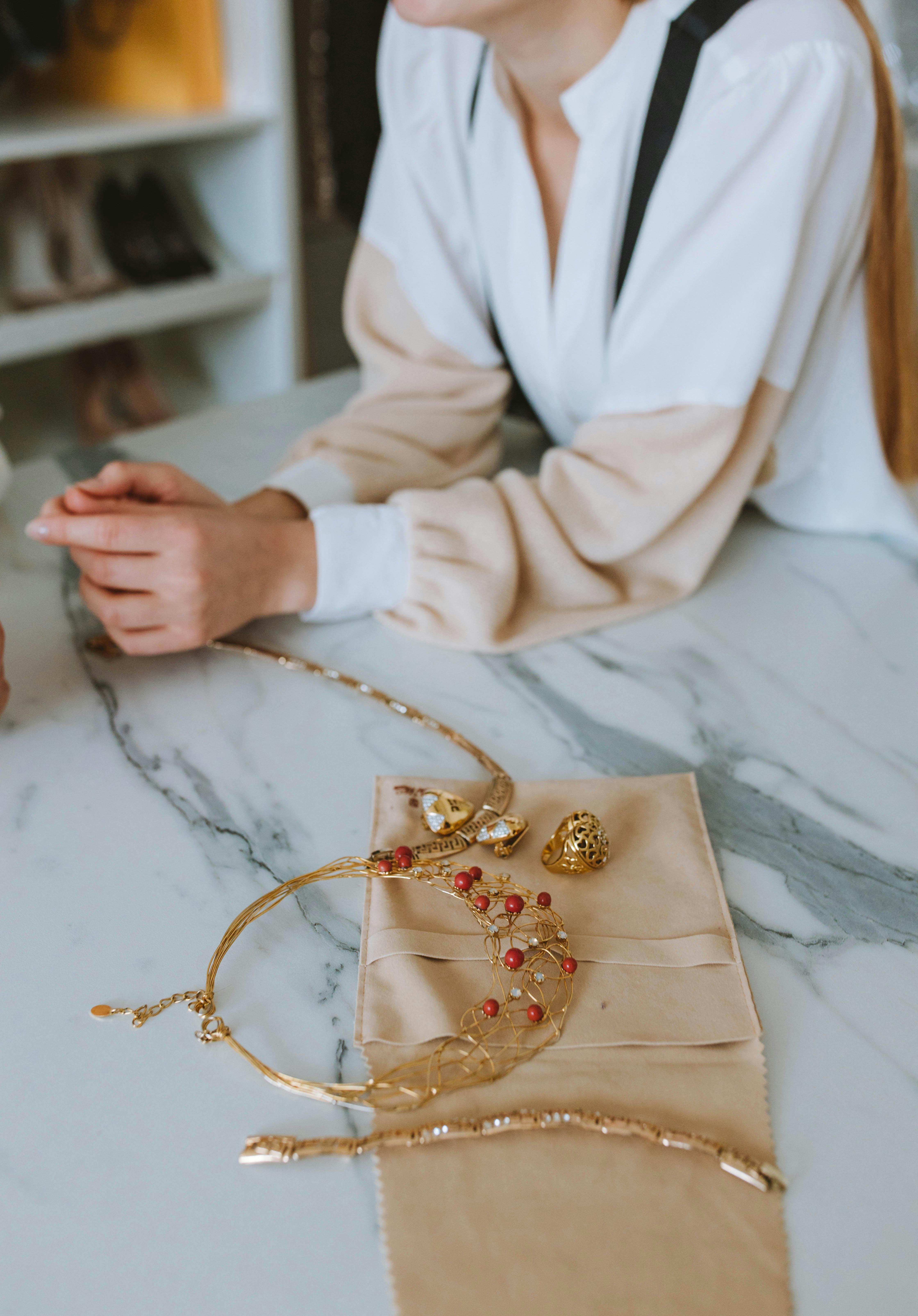 woman in white robe holding gold necklace