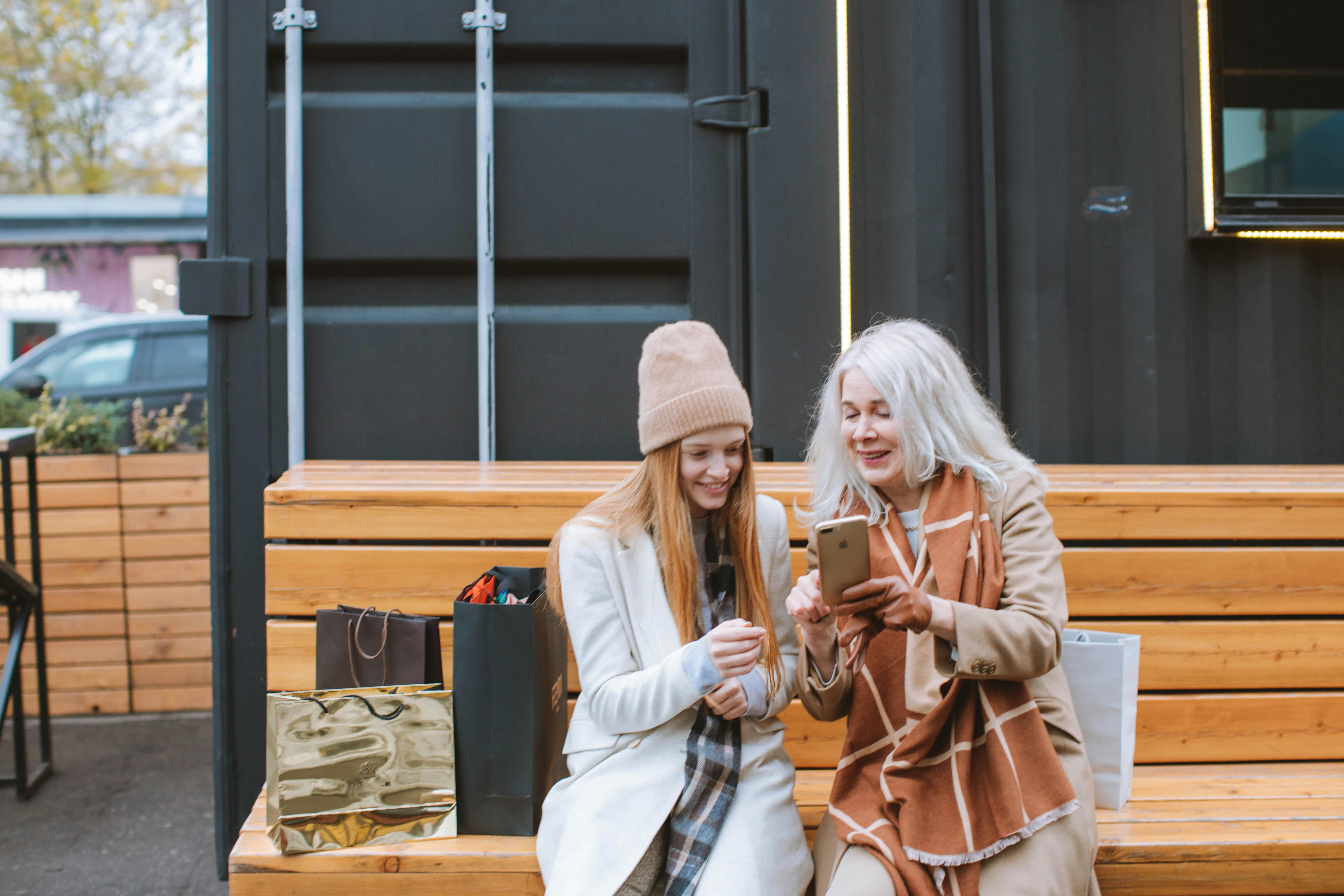 two women sitting on brown wooden bench