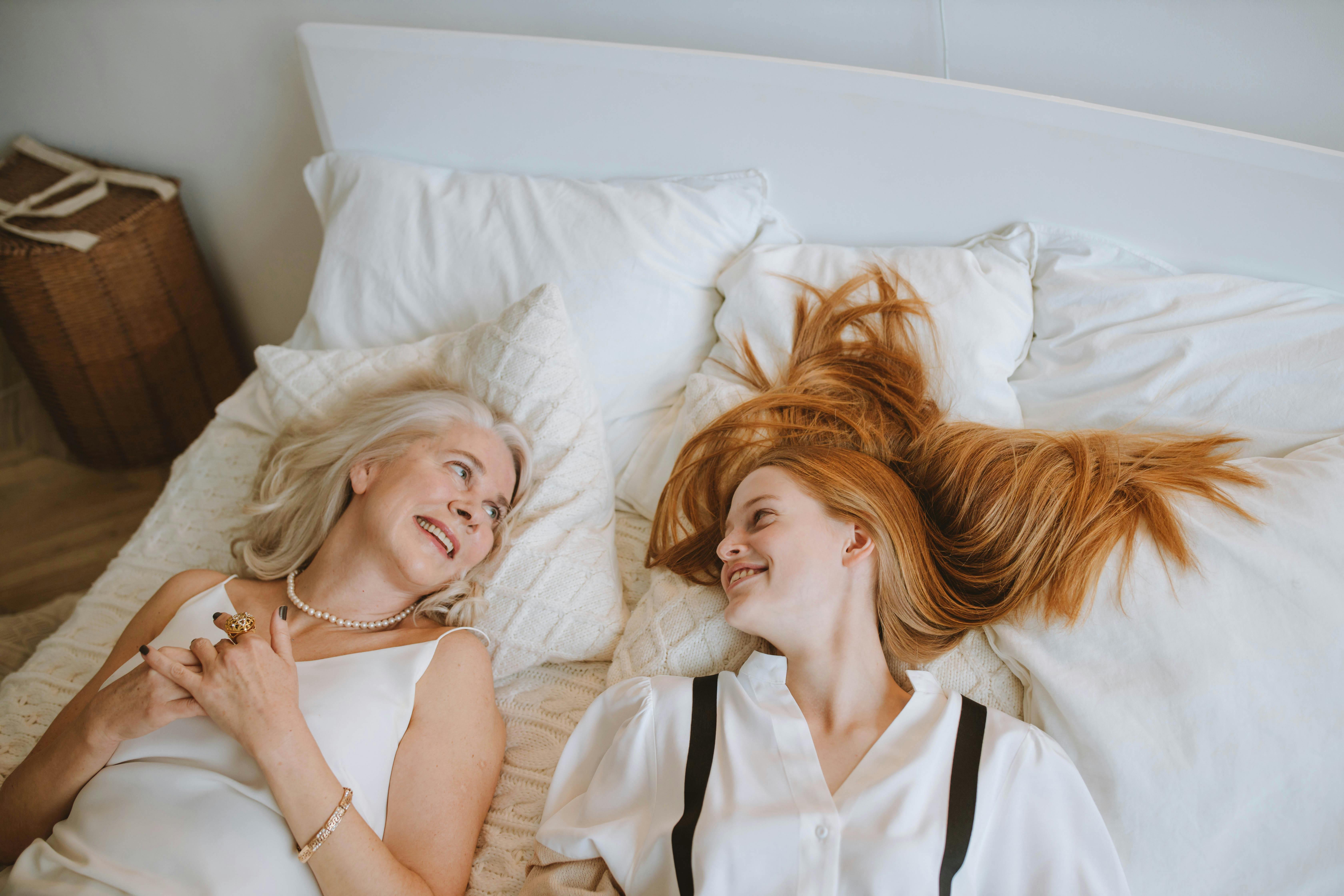 a woman lying on a bed next to her granddaughter