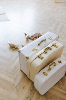 Stylish vintage suitcases with gold accents on a wooden floor, ideal for travel-themed decor.