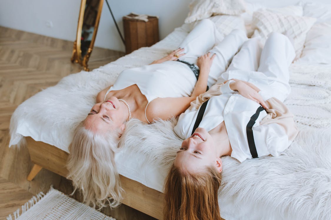 Woman in White Tank Top and Girl in White Shirt Lying on Bed