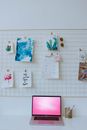 Pictures on Clips on Board Above Laptop with Pink Background
