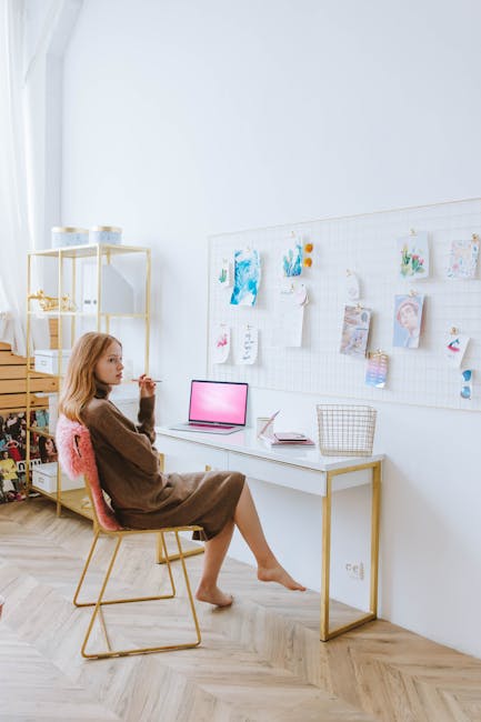 A young woman works remotely in a minimalist home office with a moodboard and laptop.