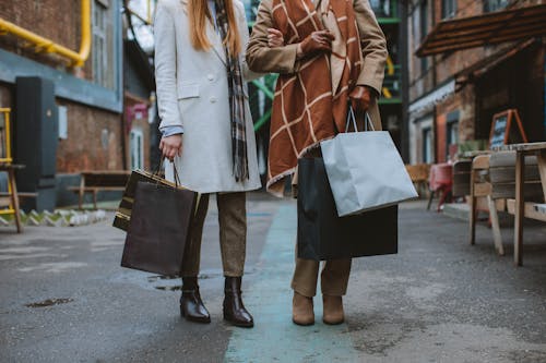 Woman in Brown Coat Holding Black Paper Bag