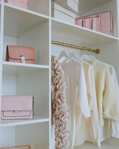 Stylish feminine wardrobe with clothes, bags, and gifts neatly organized on shelves.