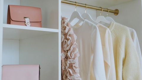 Stylish feminine wardrobe with clothes, bags, and gifts neatly organized on shelves.