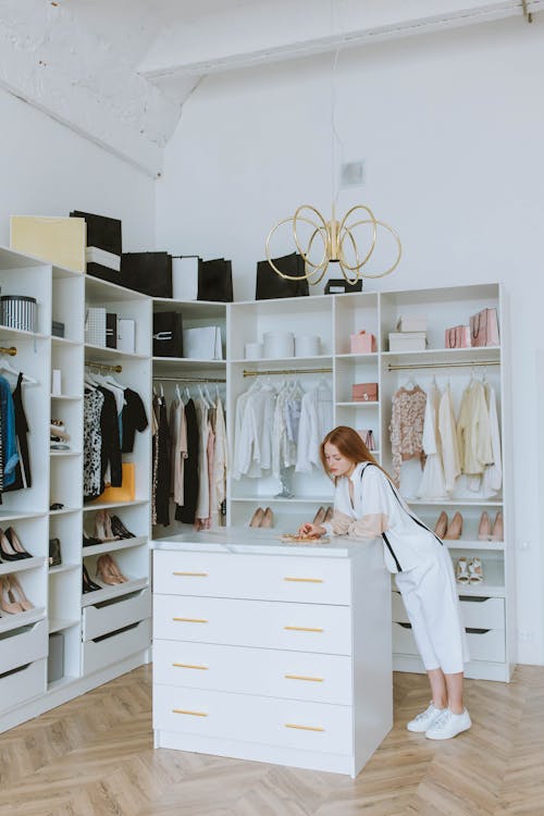 Woman in White Clothes Standing Beside White Cabinet in Wardrobe