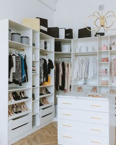 A stylish walk-in closet featuring luxury clothing, shoes, and accessories, with elegant shelving and chandeliers.