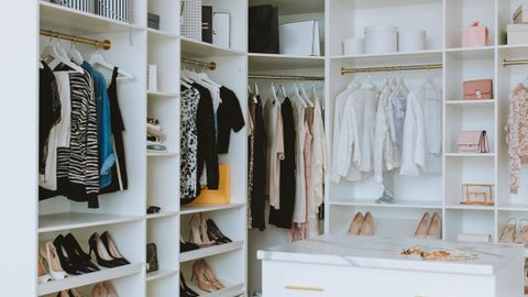 A stylish walk-in closet featuring luxury clothing, shoes, and accessories, with elegant shelving and chandeliers.