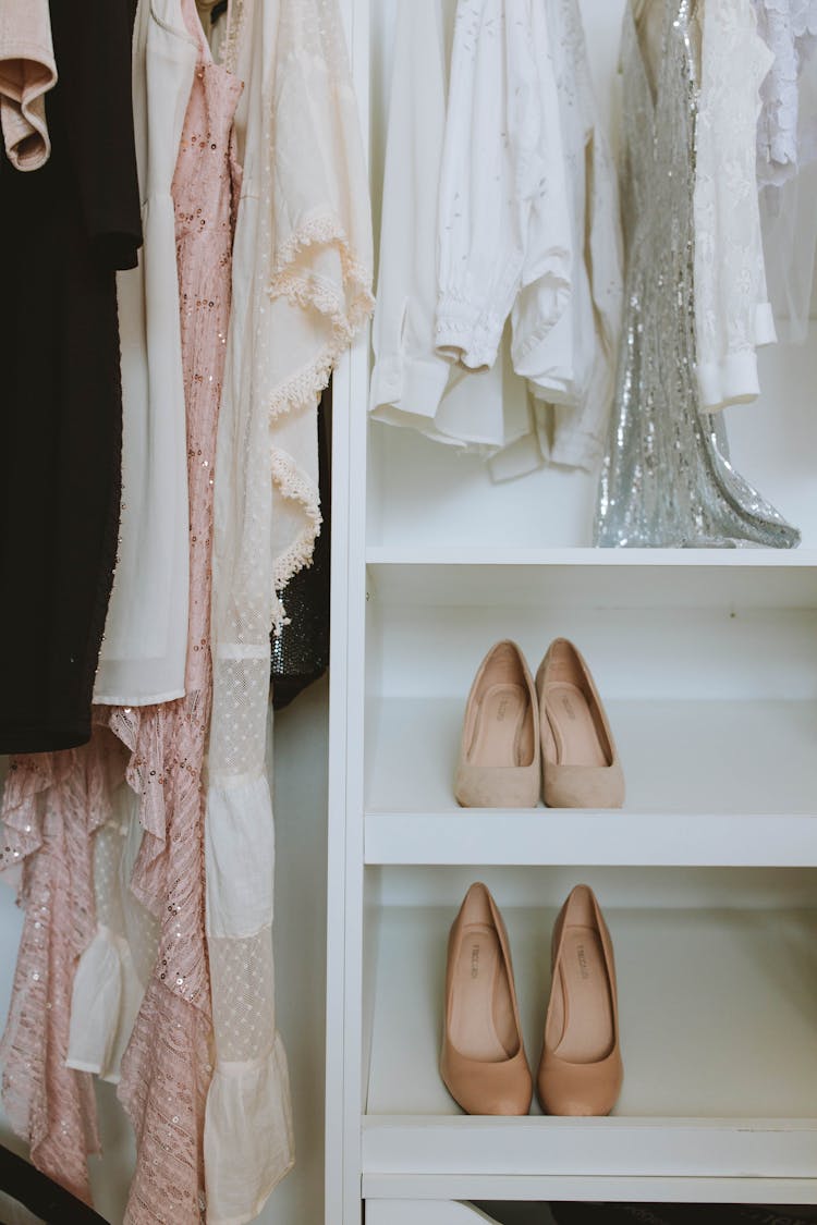 Beige Shoes On White Wooden Shelf Under Clothes 