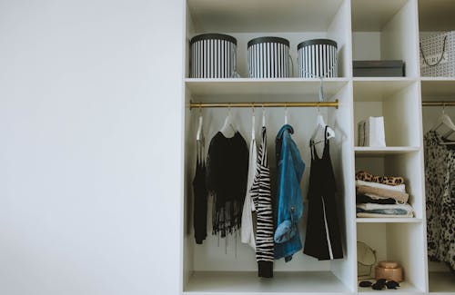 Blue and Black Clothes Hanging in White Wooden Cabinet
