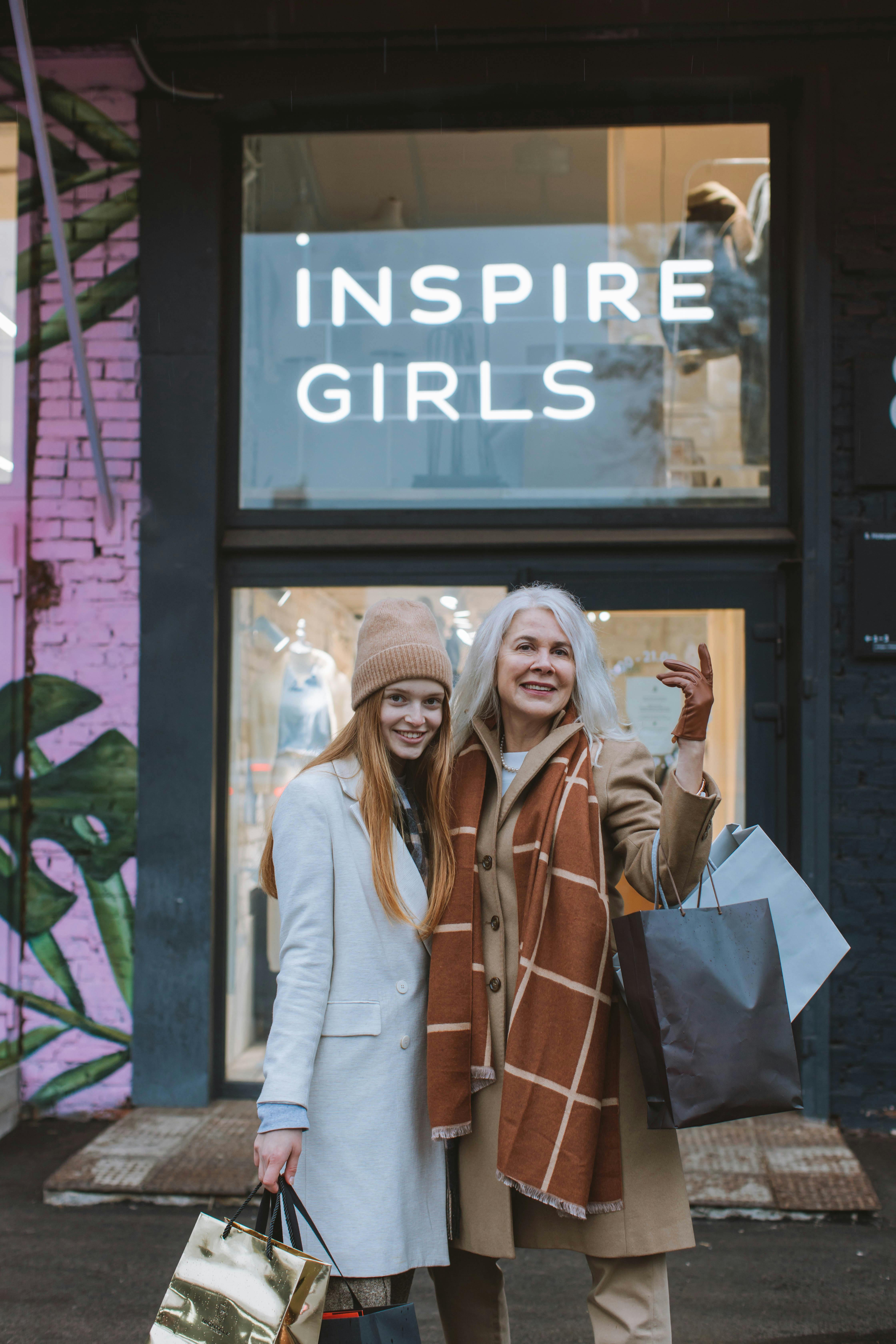 woman in white long sleeve shirt standing beside woman in brown leather jacket