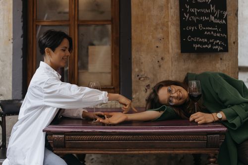Free Two women enjoying wine and laughter in a cozy café setting, fostering friendship and relaxation. Stock Photo
