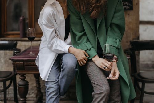 Free Two women in stylish coats, enjoying wine together in a relaxed setting. Stock Photo