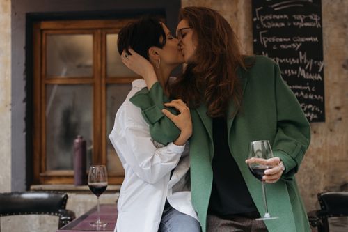 Free A loving couple shares a kiss while enjoying wine indoors. Stock Photo