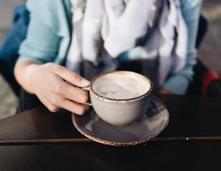 A person holding a cappuccino cup in a relaxing outdoor setting. Perfect for lifestyle content.