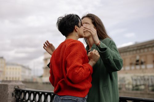 Free A loving lesbian couple sharing a tender kiss against a city backdrop. Stock Photo