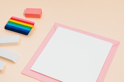 White Blank Card on Pink Envelope Beside Erasers