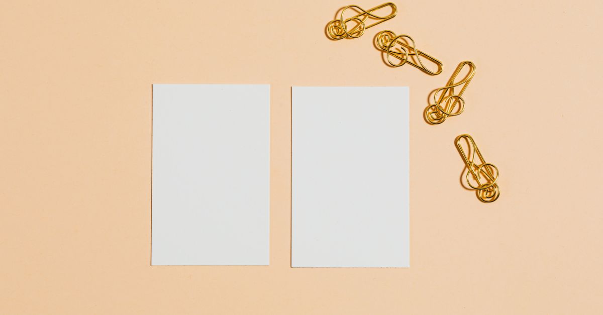 Minimalist design with blank cards and gold paper clips on a peach background.
