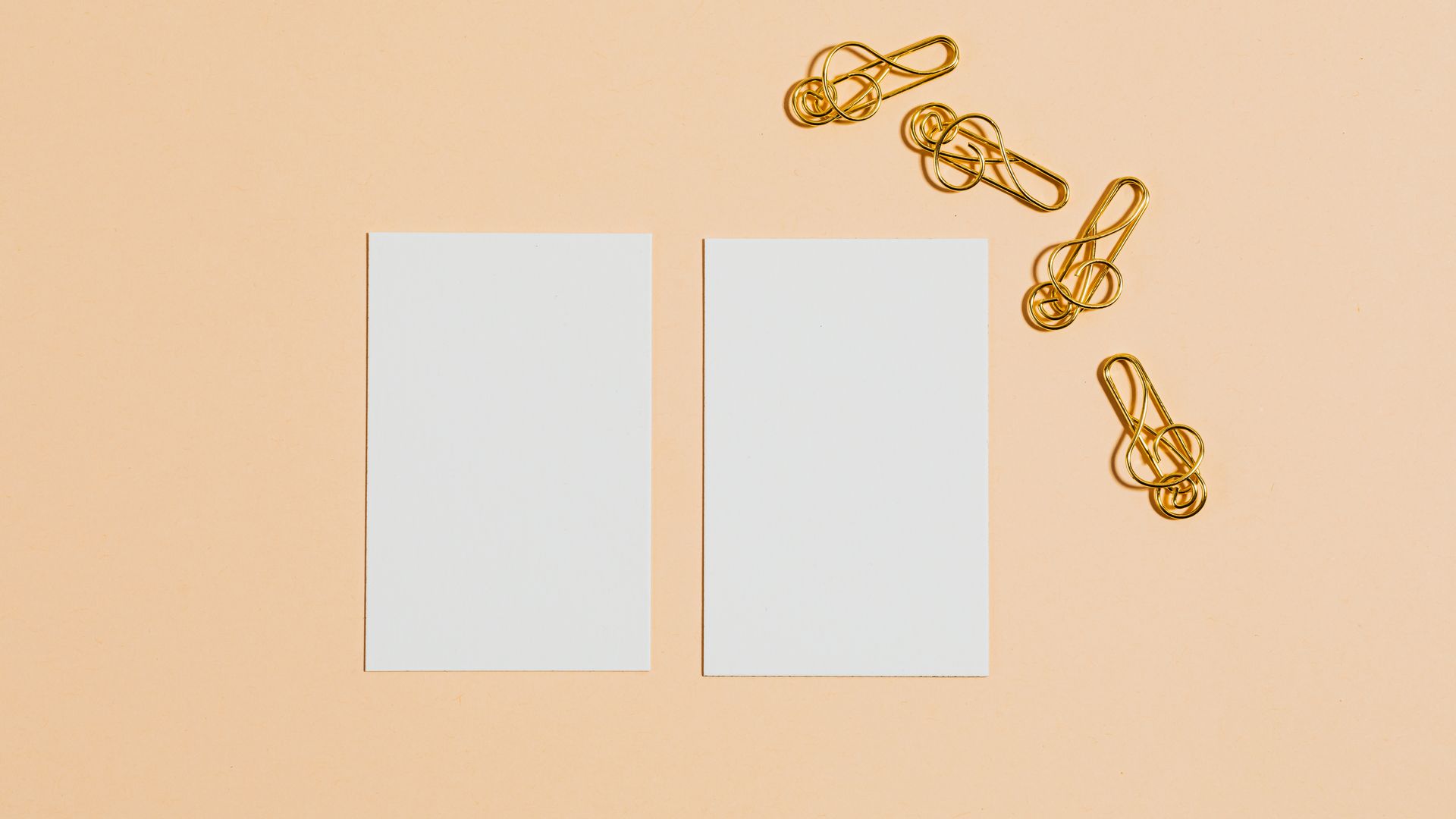 Business Cards: Your Ultimate Networking Tool 3 Minimalist design with blank cards and gold paper clips on a peach background — business cards