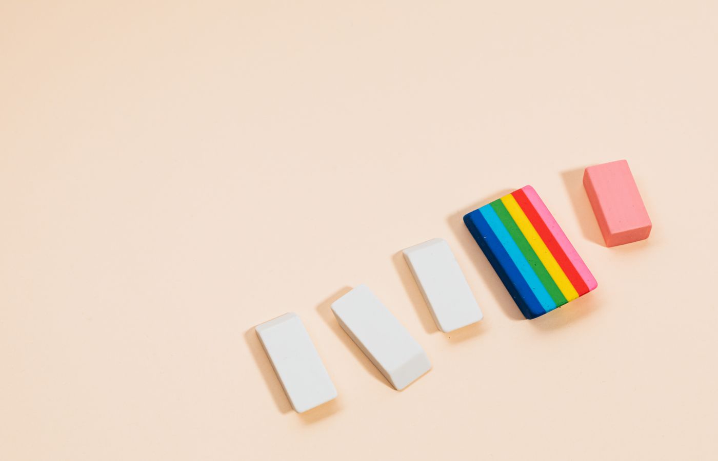 Close-up of various colorful erasers on a pastel beige background, perfect for school themes.