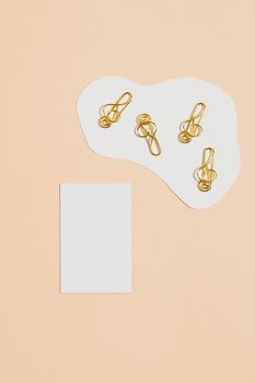 米色背景上，金色曲别针的抽象构图复制出空间感