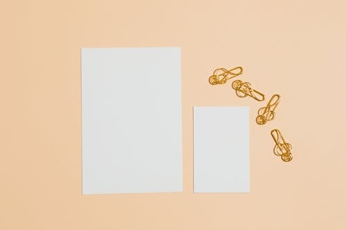 Photo of Gold Paper Clips Near Blank Cards