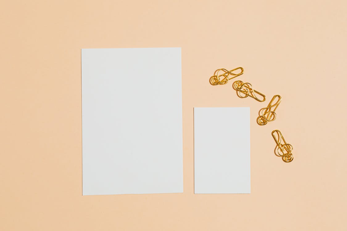 Photo of Gold Paper Clips Near Blank Cards