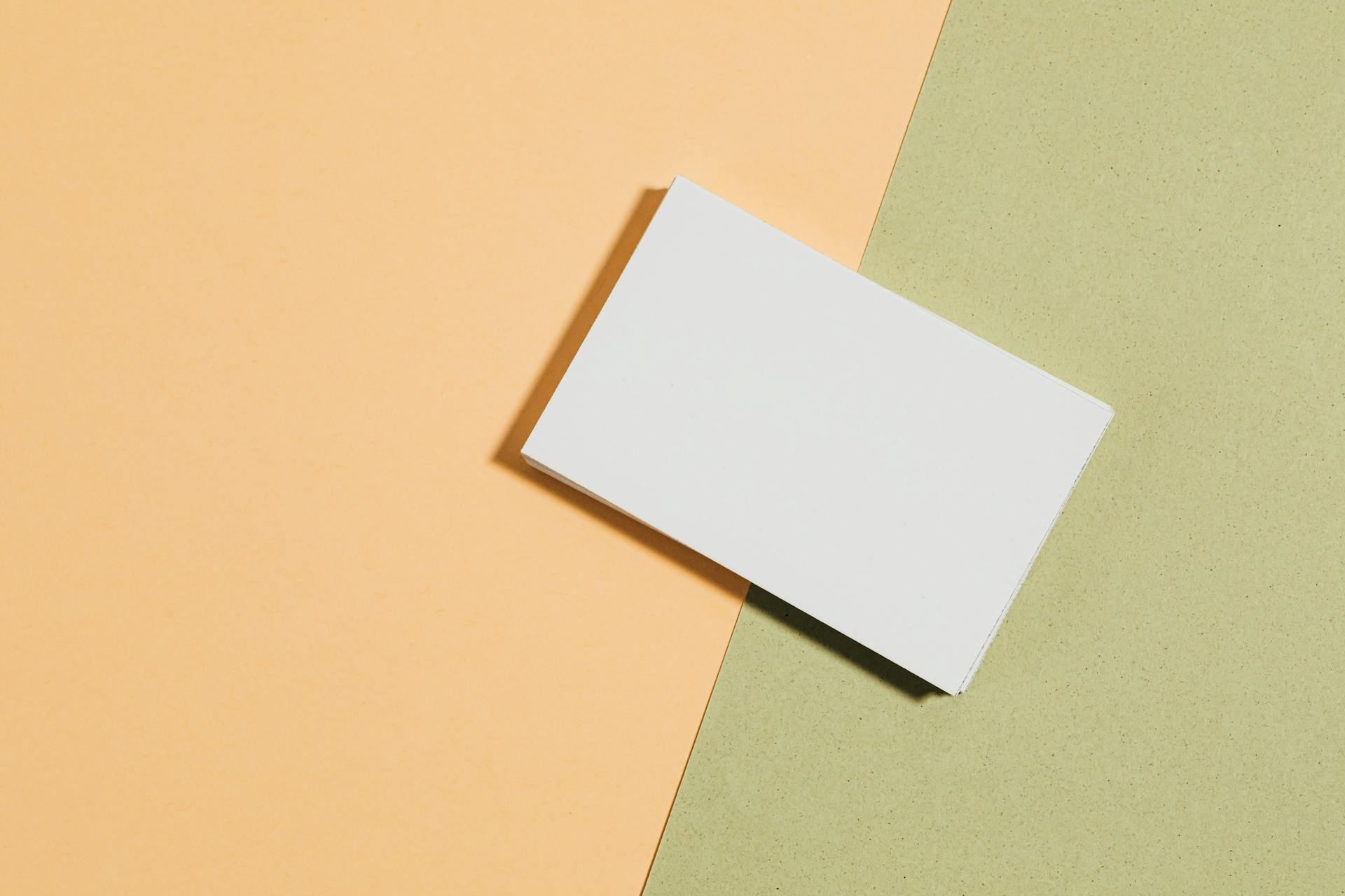 Top-down view of a business card on pastel backgrounds, perfect for branding and design concepts.