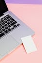 一张配有白纸的银色笔记本电脑极简照片，采用粉紫色调，凸显了现代科技感