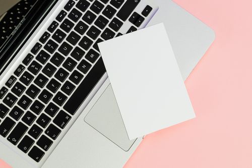 Free A blank card placed on a laptop keyboard with ample copy space on a pastel background. Stock Photo