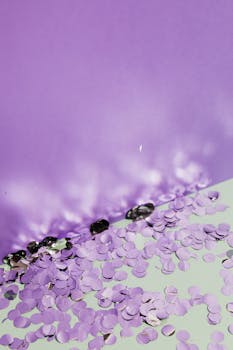 丁香色的背景上，散落着闪闪发光的紫色五彩纸屑，营造出喜庆而俏皮的场景