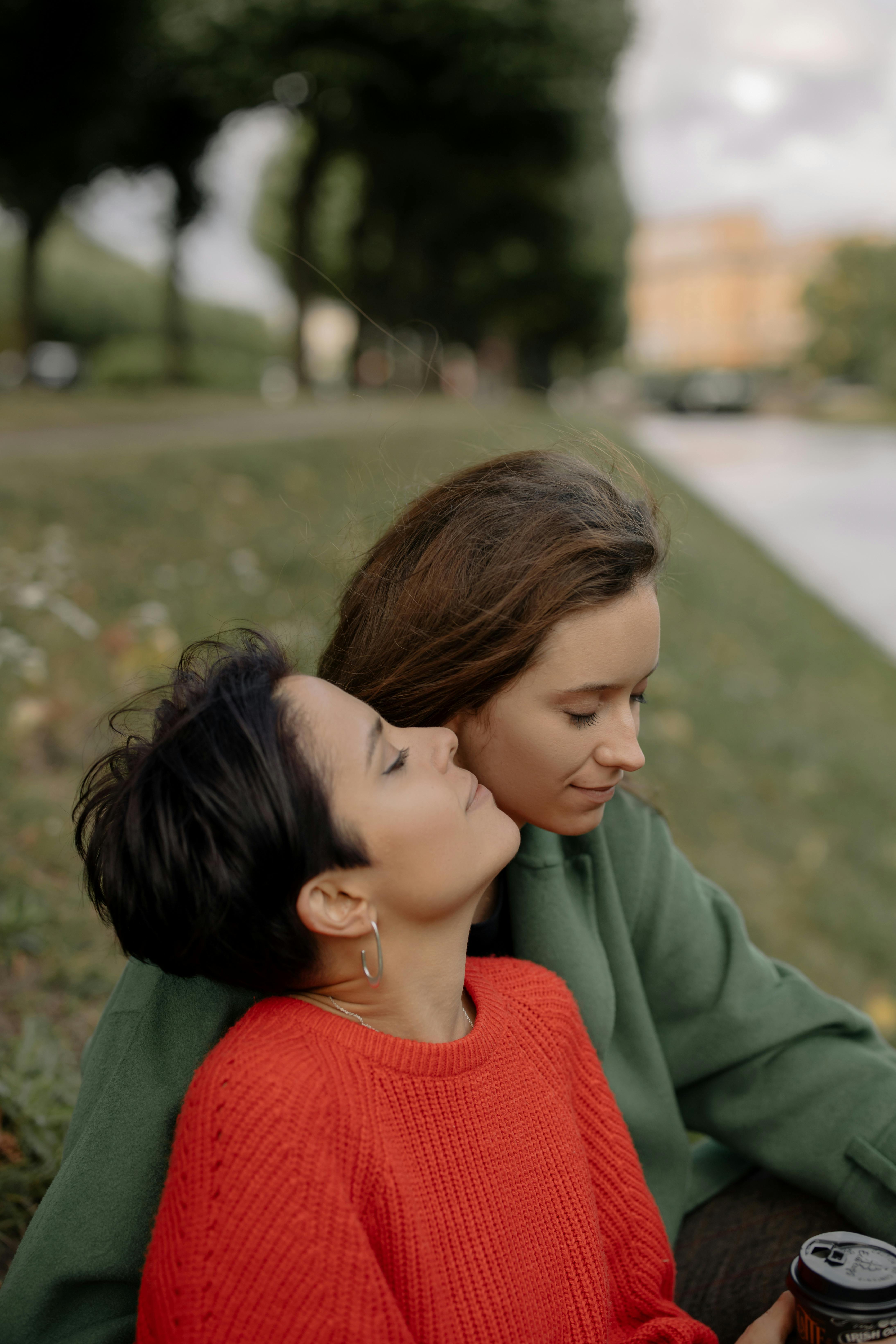 girl in red shirt kissing girl in green jacket