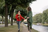 一对快乐的女同性恋夫妇捧着鲜花，在风景优美的公园里散步