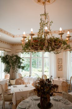 这家奢华的餐厅配有装饰着绿色元素的枝形吊灯，餐桌布置也十分优雅