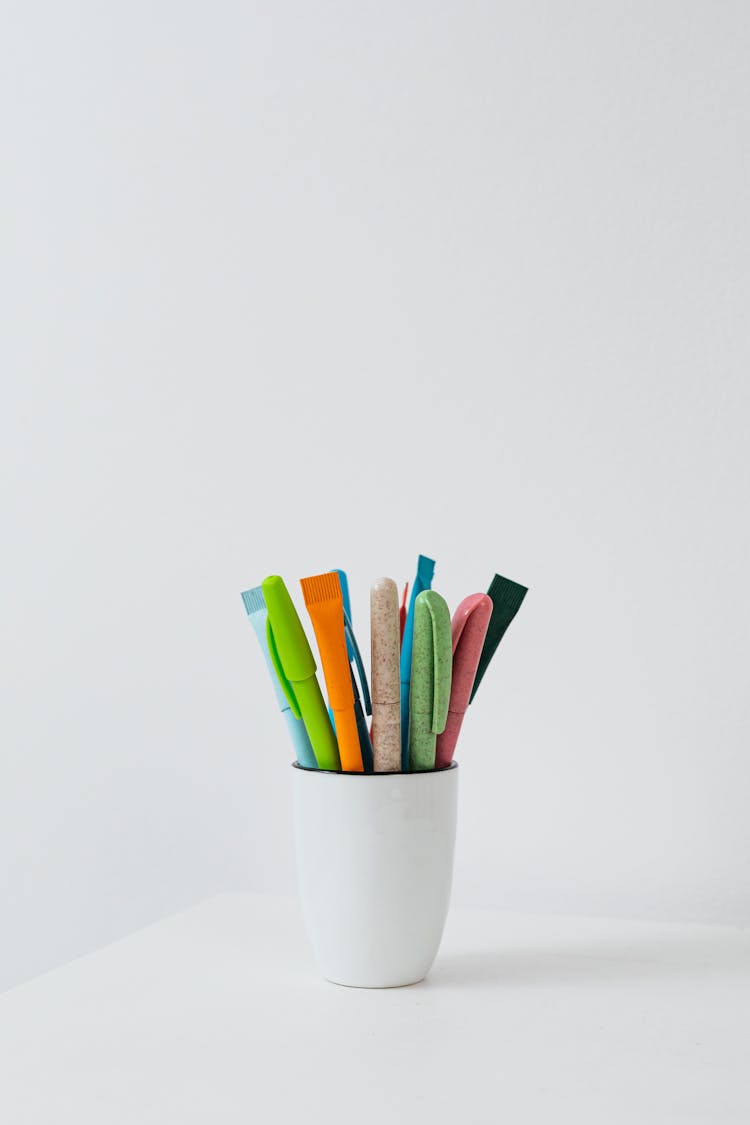 Colorful Pens In White Ceramic Cup